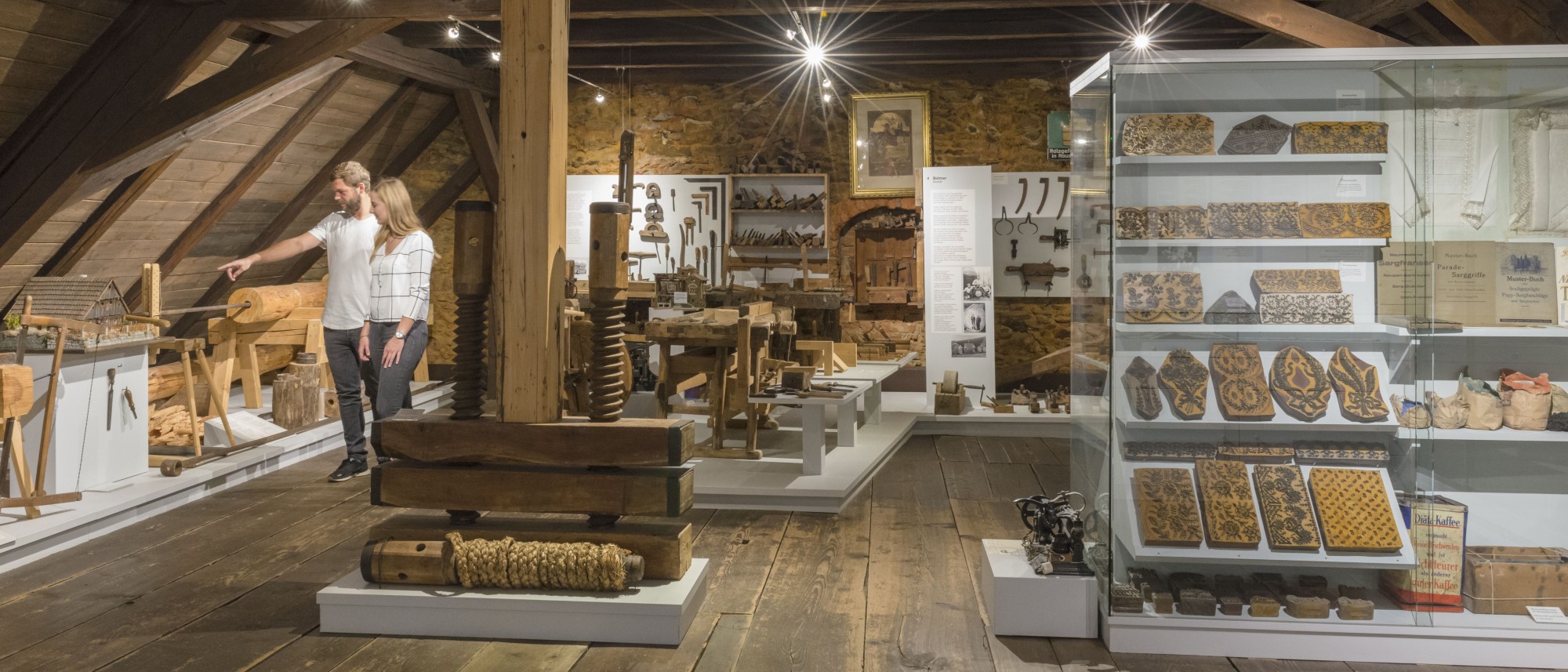Zwei Personen in der Abteilung historisches Handwerk im Stiftlandmuseum, dort sind Werkzeuge und Druckmodel zu sehen