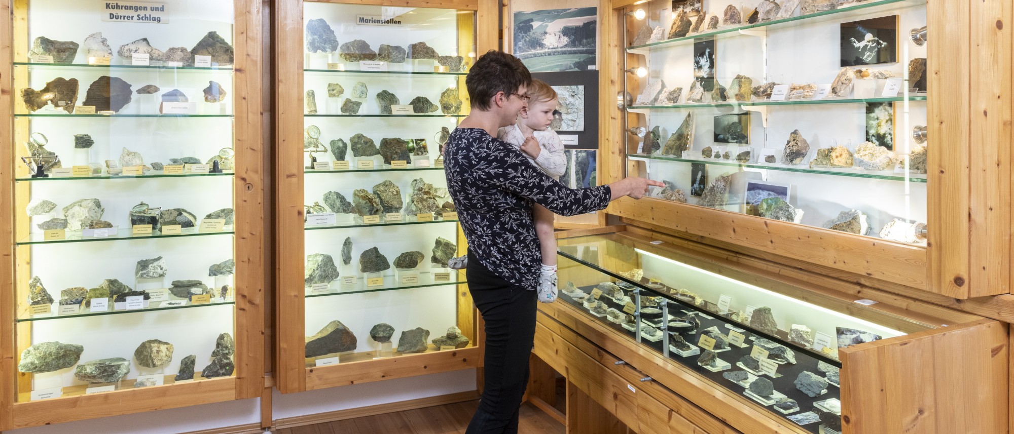 Frau mit Kind sehen sich Mineralien in der Ausstellung an